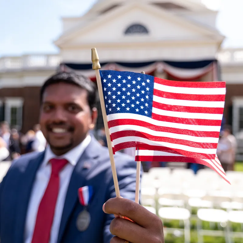 A man smiles and holds an American flag