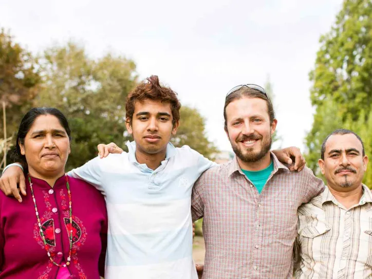 Four people stand outside and smile in front of an IRC New Roots space