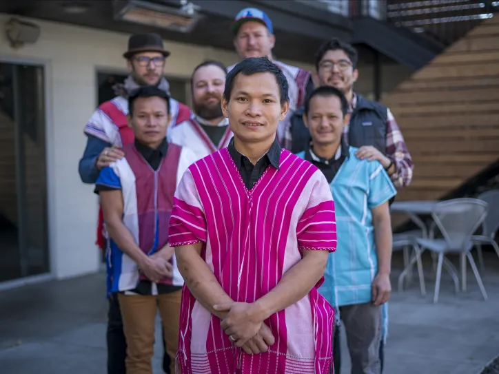 Dah Bu and his coworkers stand together for a group photo. Dah Bu and his friends are wearing traditional Burmese outfits. 