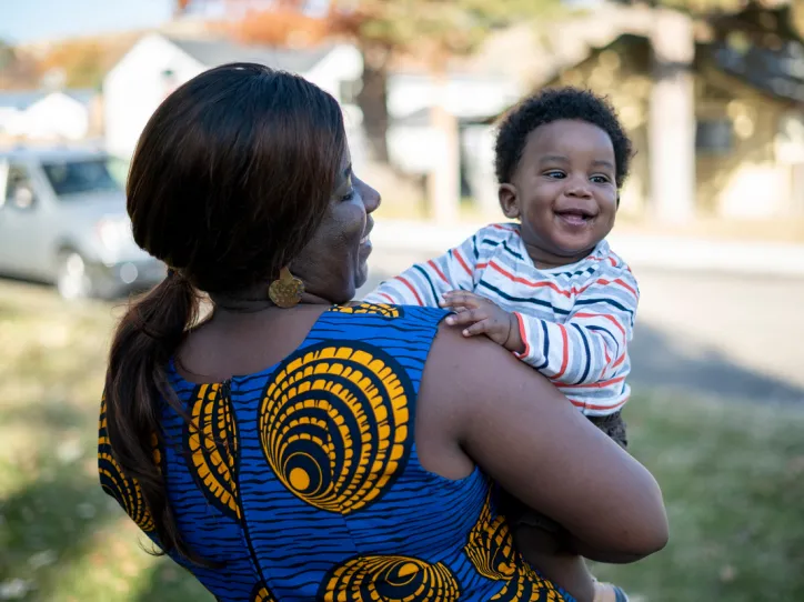 Jacqueline stands outside her home with her son, Zoe who is one.