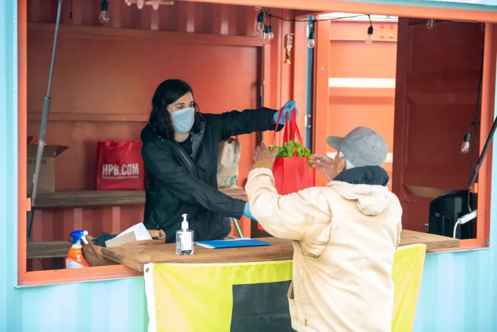 An IRC staff member hands a client a tote bag with a week's worth of food