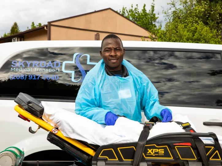 A man stands next to a stretcher as part of his job as a medical transporter