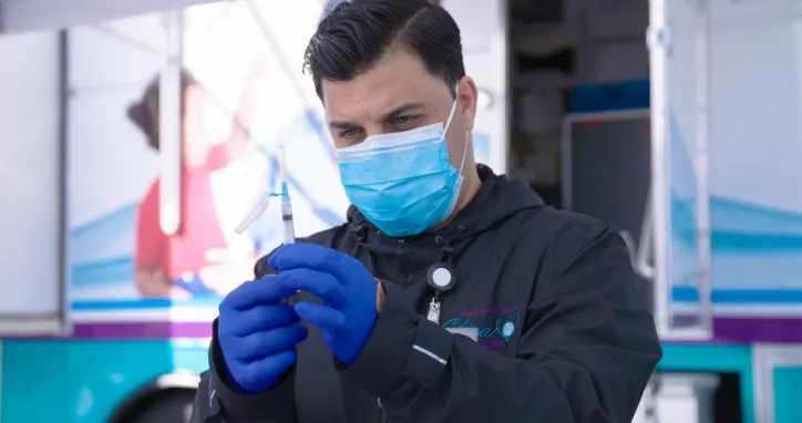 Ajmal, a medical assistant and IRC client, gives a COVID vaccine to a patient at a mobile medical clinic