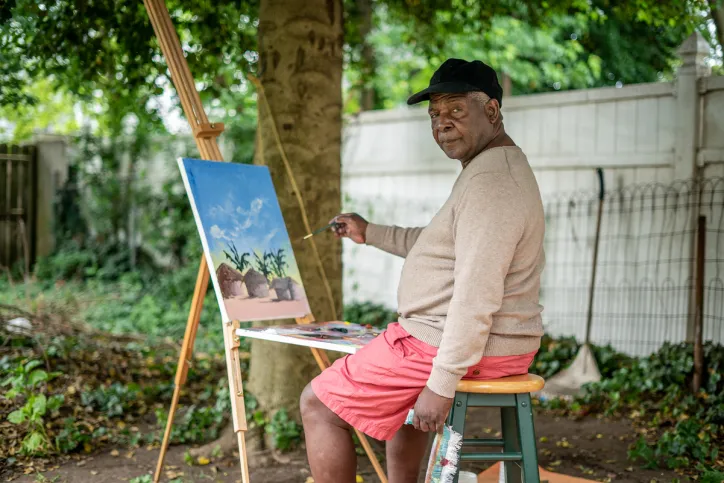 A man sits outside and paints