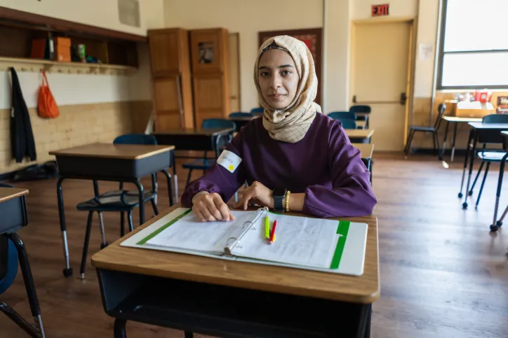 A youth girl sits at a desk in a classroom