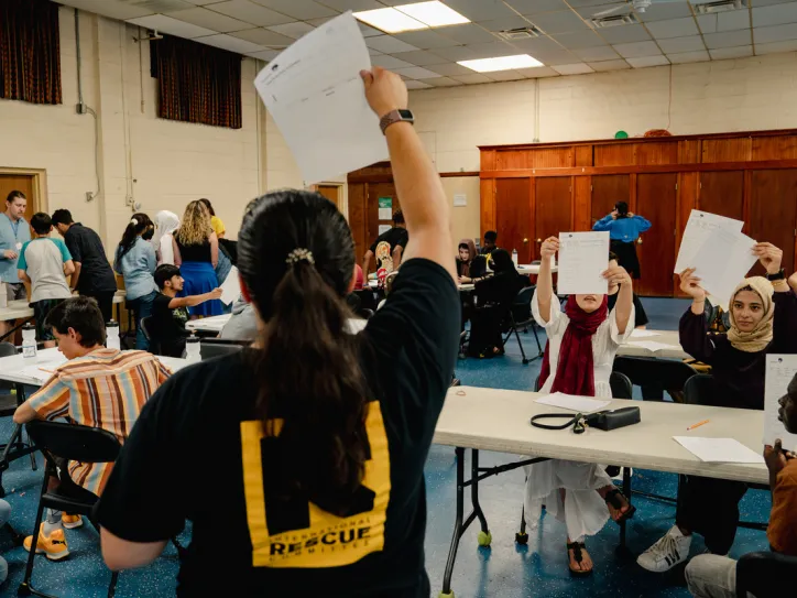 Students show their assessments to a staffer