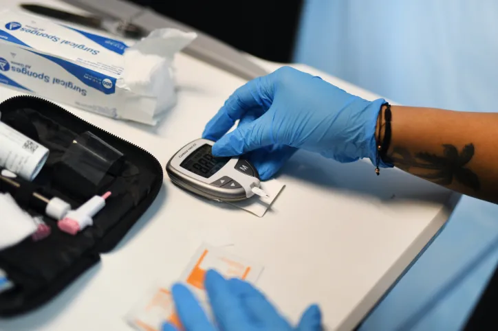  A healthcare professional sets up a blood glucose meter to test someone's glucose levels.