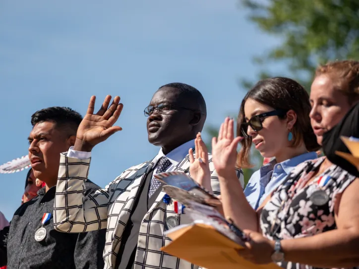 Four people stand with their right hands raised in a naturalization ceremony in Charlottesville