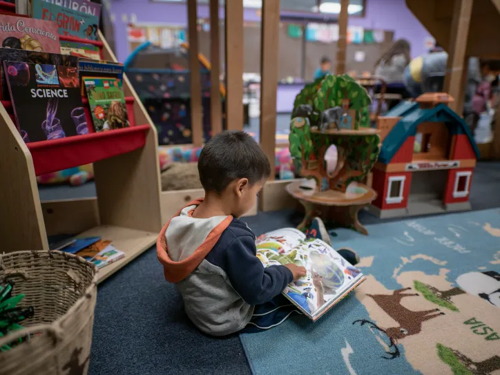 A small boy sits and reads a book