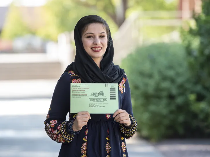 A woman holds up her ballot to vote in an election