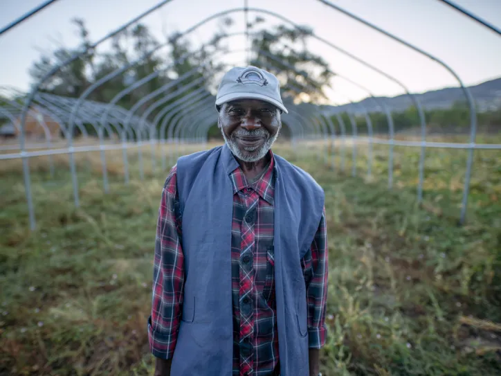 A man smiles in front of a New Roots garden