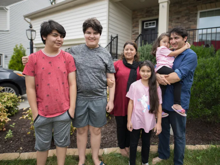 A family stands together outside their house