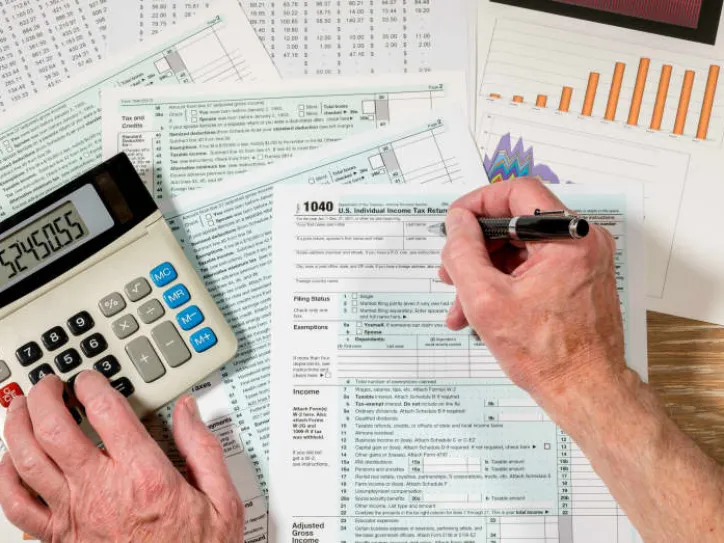 A hand writes down numbers on a tax filing page