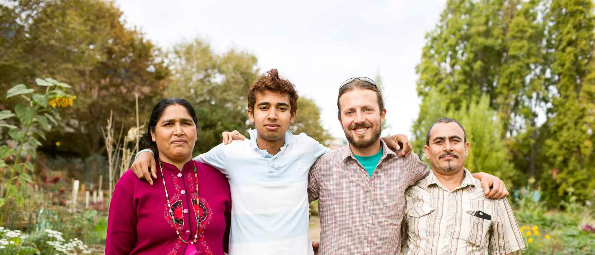 Four people stand outside and smile in front of an IRC New Roots space
