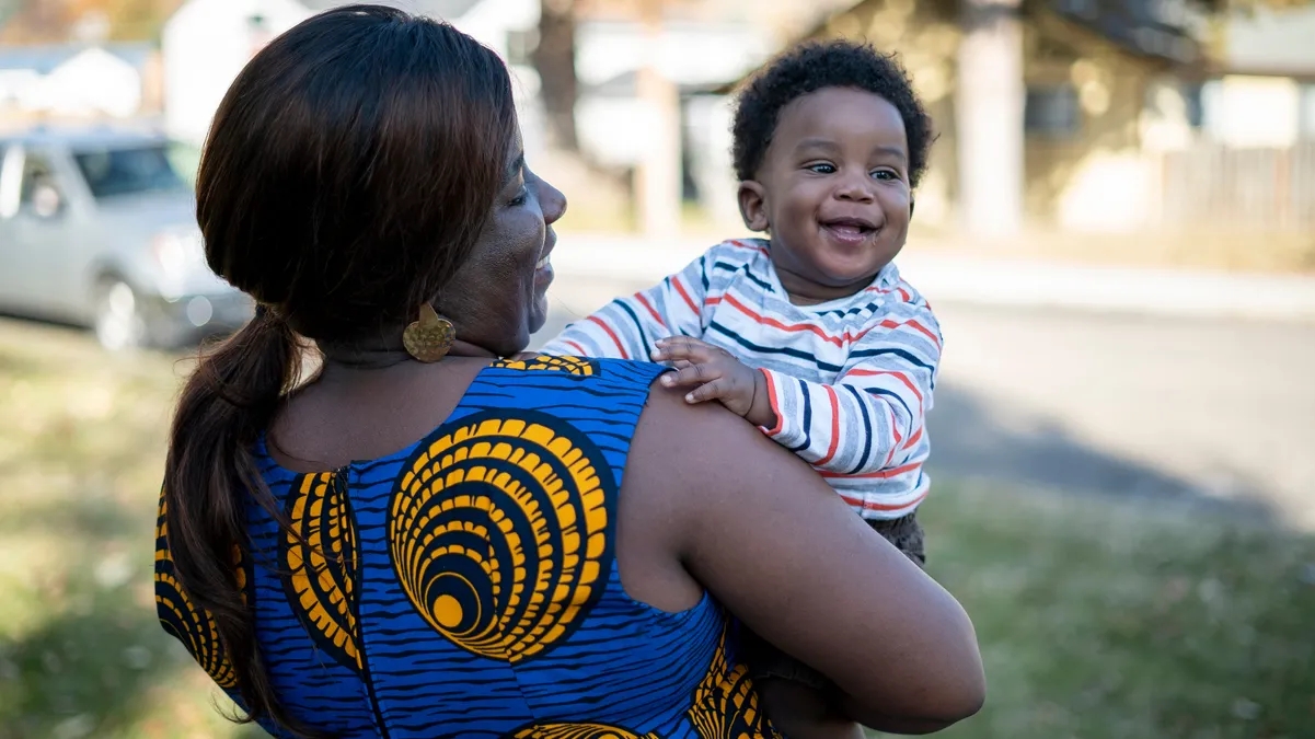 Jacqueline stands outside her home with her son, Zoe who is one.