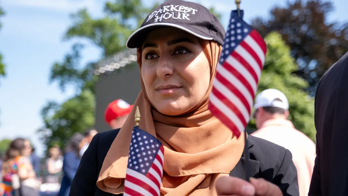 A woman stands with two miniature American flags