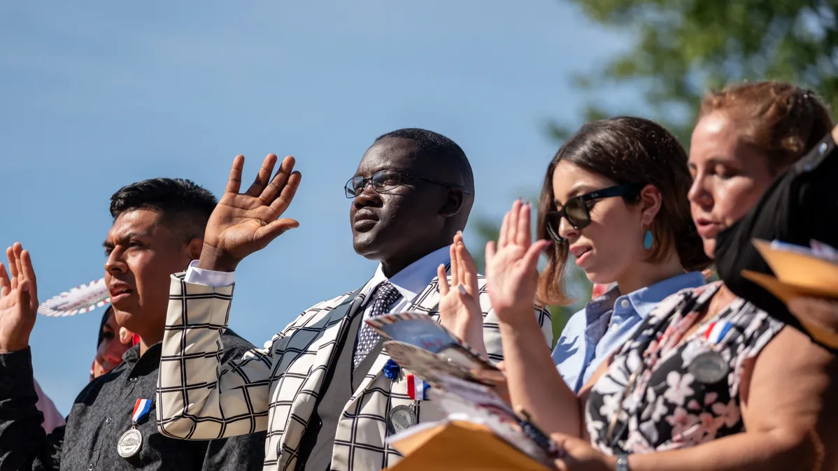 Four people stand with their right hands raised in a naturalization ceremony in Charlottesville