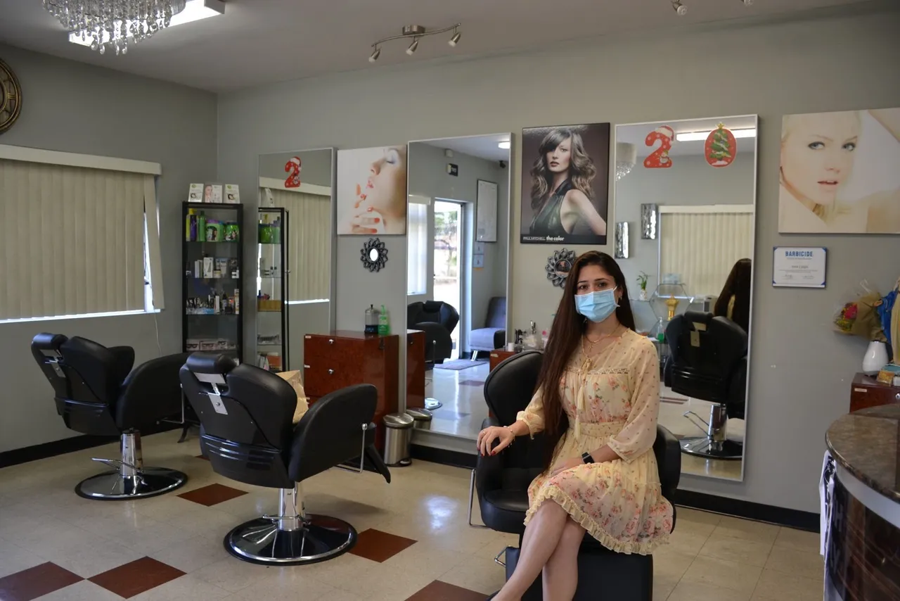 A woman sits in the salon where she works
