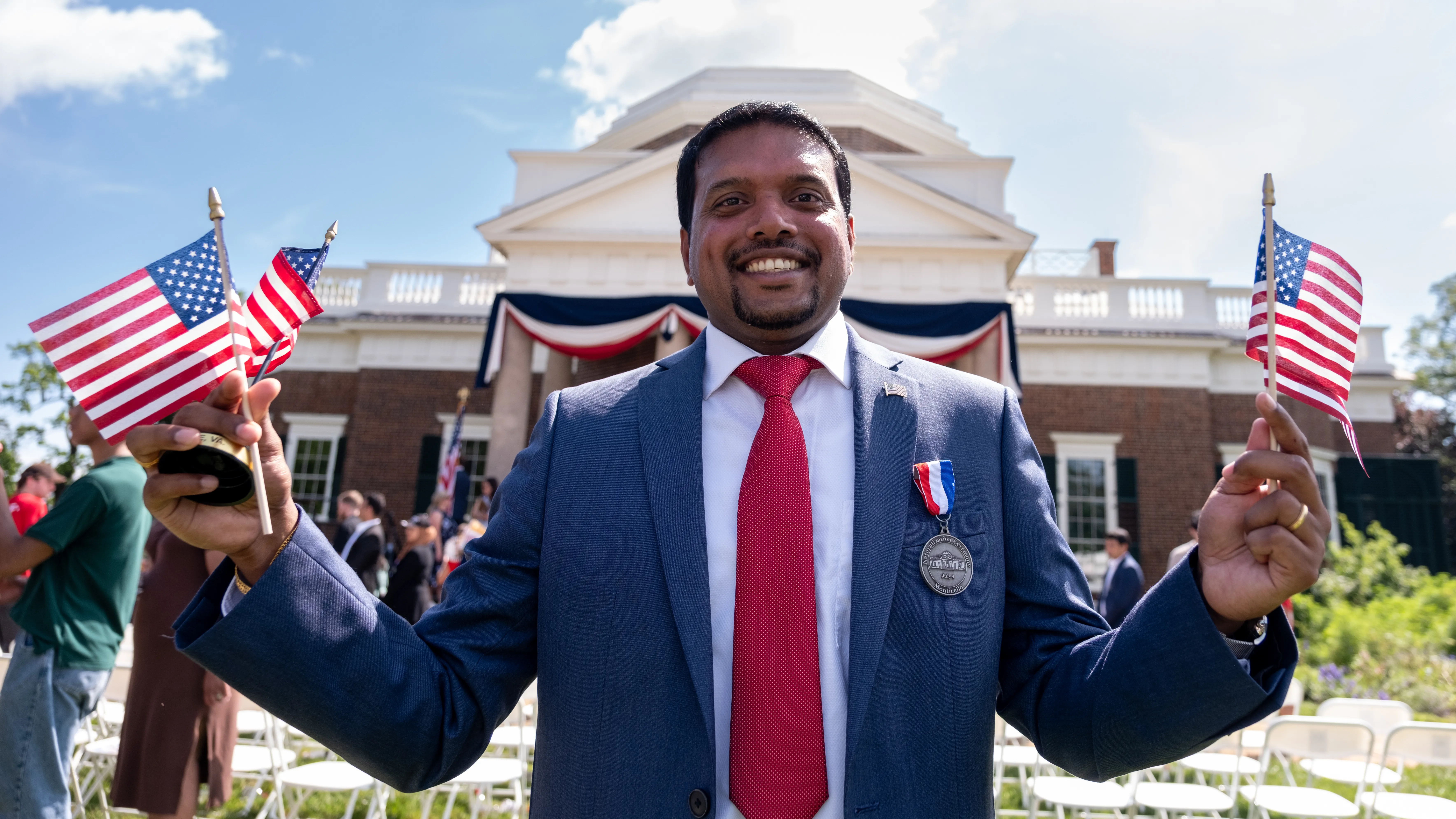 Happy man with US flagsin front of Monticello in Charlottesville, VA, USA