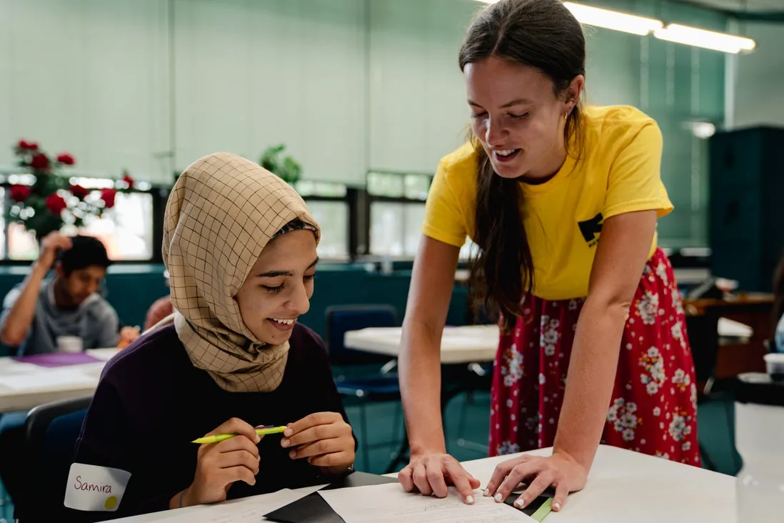 An English language learner and instructor smile and look at a paper