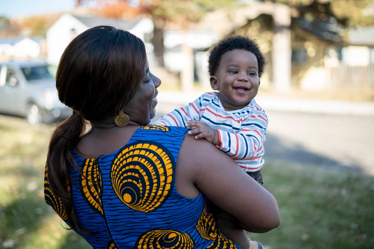Jacqueline stands outside her home with her son, Zoe who is one.