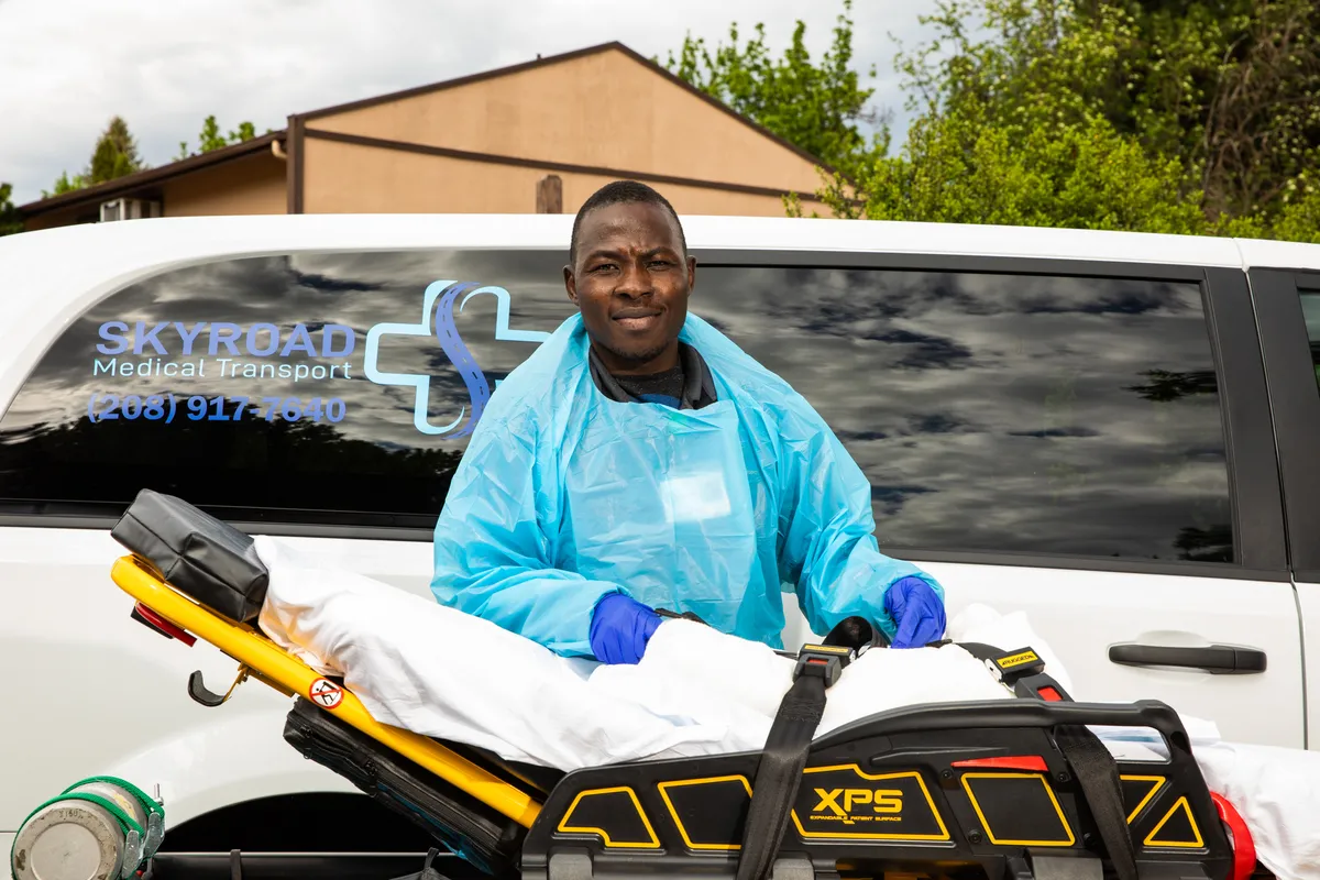 A man stands next to a stretcher as part of his job as a medical transporter