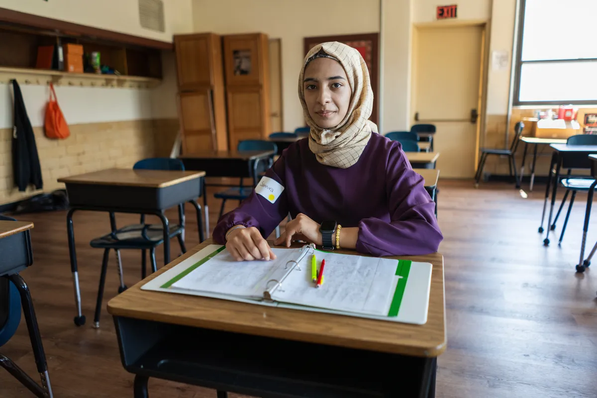 A youth girl sits at a desk in a classroom