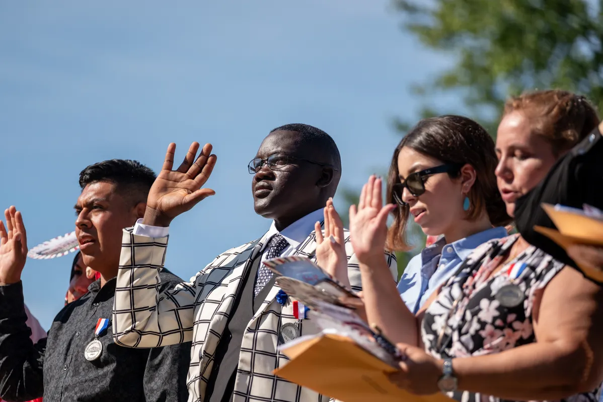 Four people stand with their right hands raised in a naturalization ceremony in Charlottesville