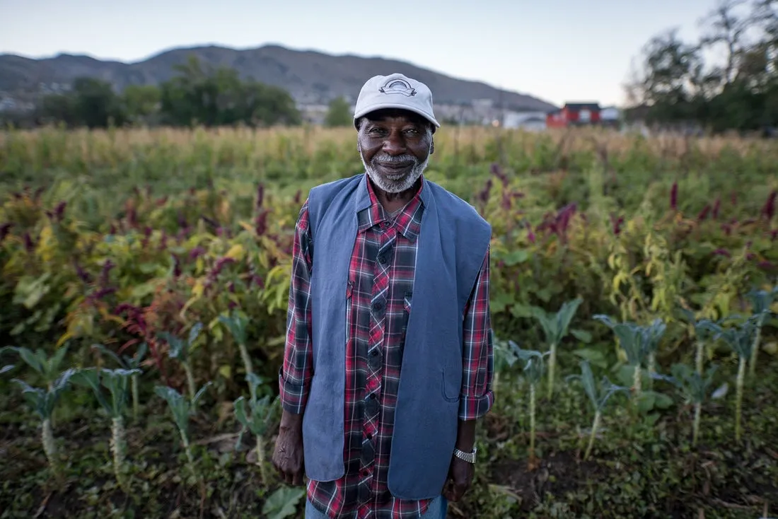 Man smiles in front of fruit and vegetable field 