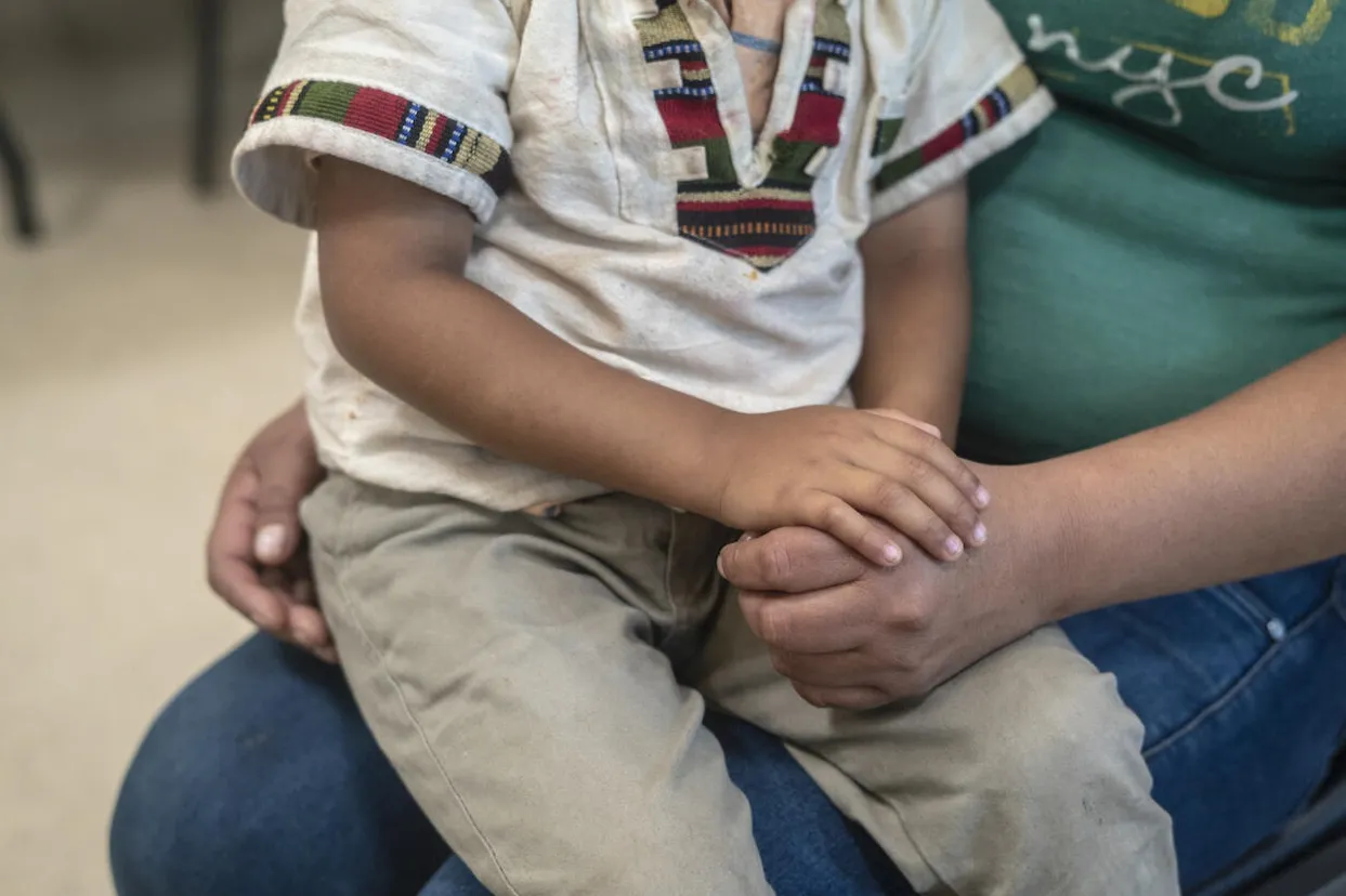 A child sits on his mother's lap