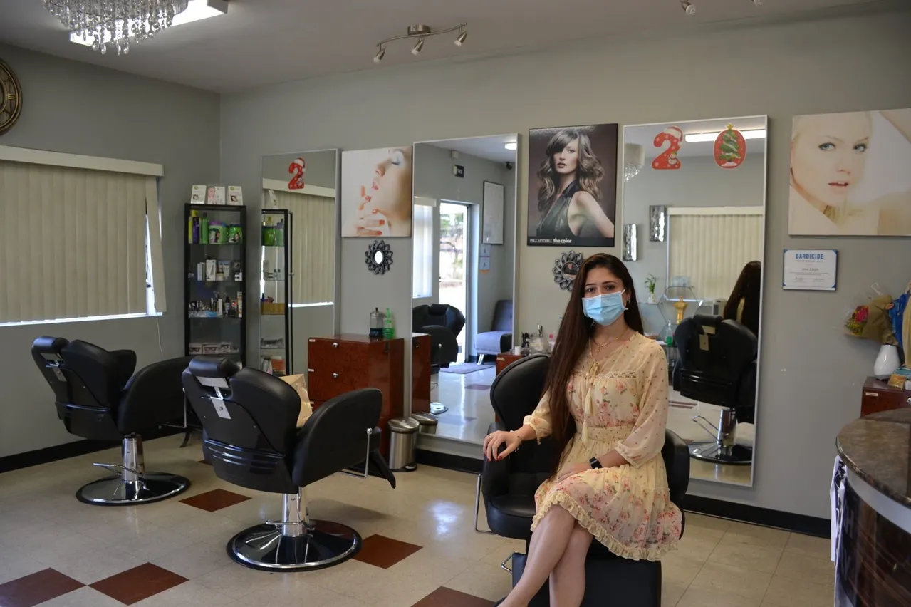A woman sits in the salon where she works