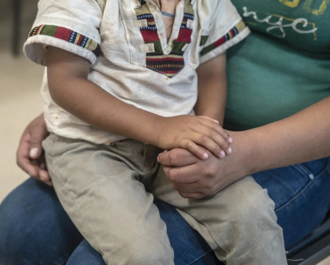 A child sits on his mother's lap